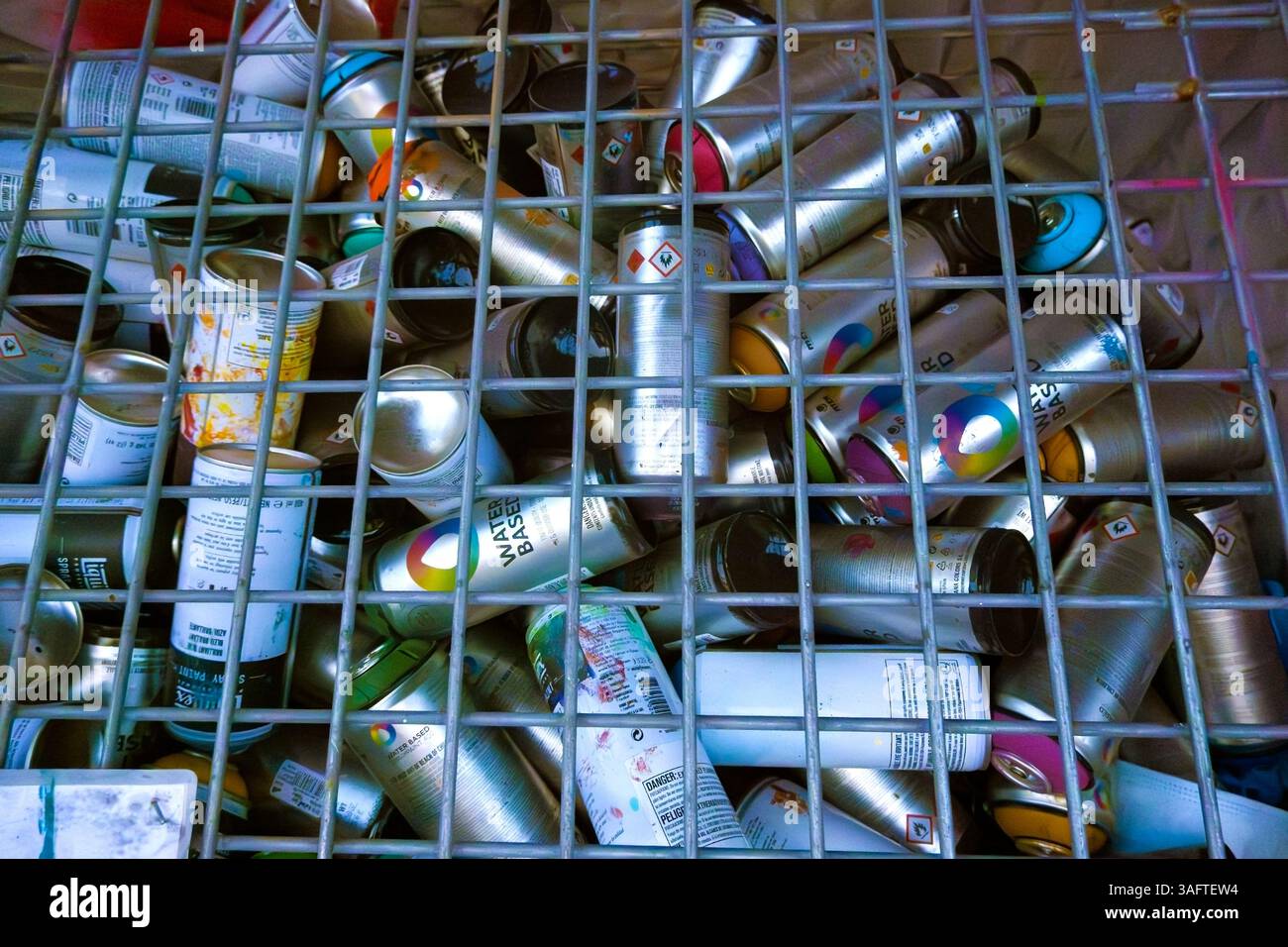 Pulvérisateurs de peinture usagés sous une grille métallique Banque D'Images