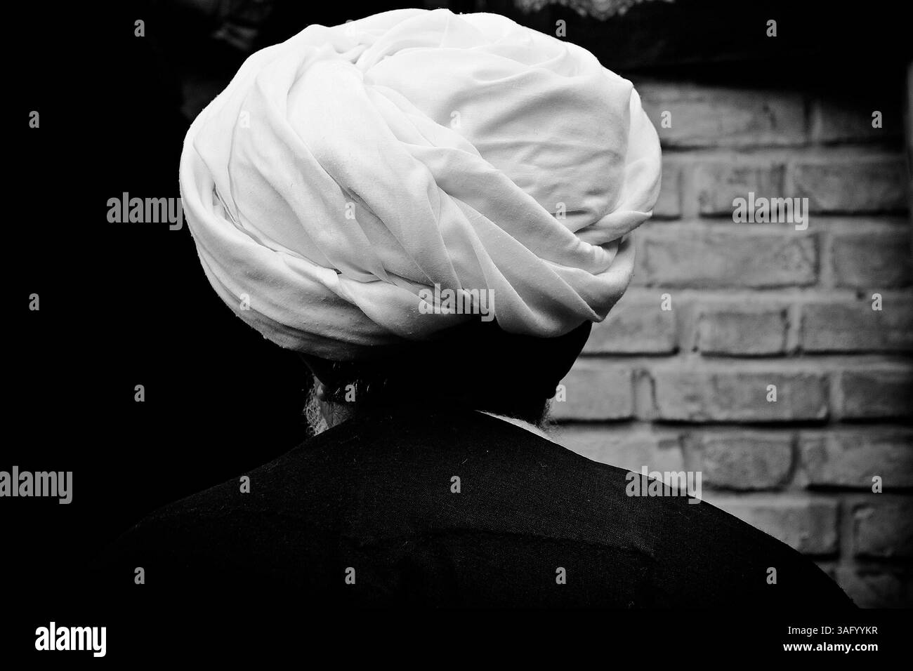 Dec. 5, 2011 - Khorramabad, Iran - Mullah par derrière. Chaque année pour marquer la mort de l'imam Hussein, les musulmans chiites pleurent pendant deux jours. À Khorramabad et Lorestan, dans l’ouest de l’Iran, lors du premier jour de deuil, appelé Tasooa, les femmes font vœu de silence et traversent les rues avec les enfants allumant des bougies. À 4 heures du matin sur Ashura, le deuxième jour, les hommes se couvrent de boue et se tiennent devant un feu jusqu'à ce que la boue ait séché pour devenir argile. Après cela, ils vont à la mosquée et prient (crédit image : © Farhad Babaei/ZUMAPRESS.com) Banque D'Images