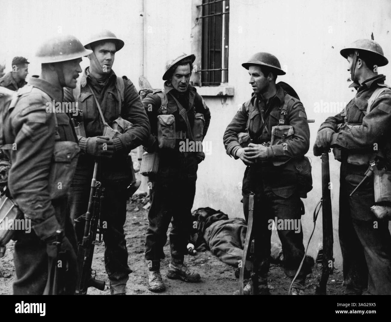 Ces hommes d'un régiment canadien en Italie viennent d'aider à capturer une unité du quartier général allemand. Un officier allemand mort se trouve derrière eux. 26 mars 1945. (Photo de Canadian W.I.B.). Banque D'Images