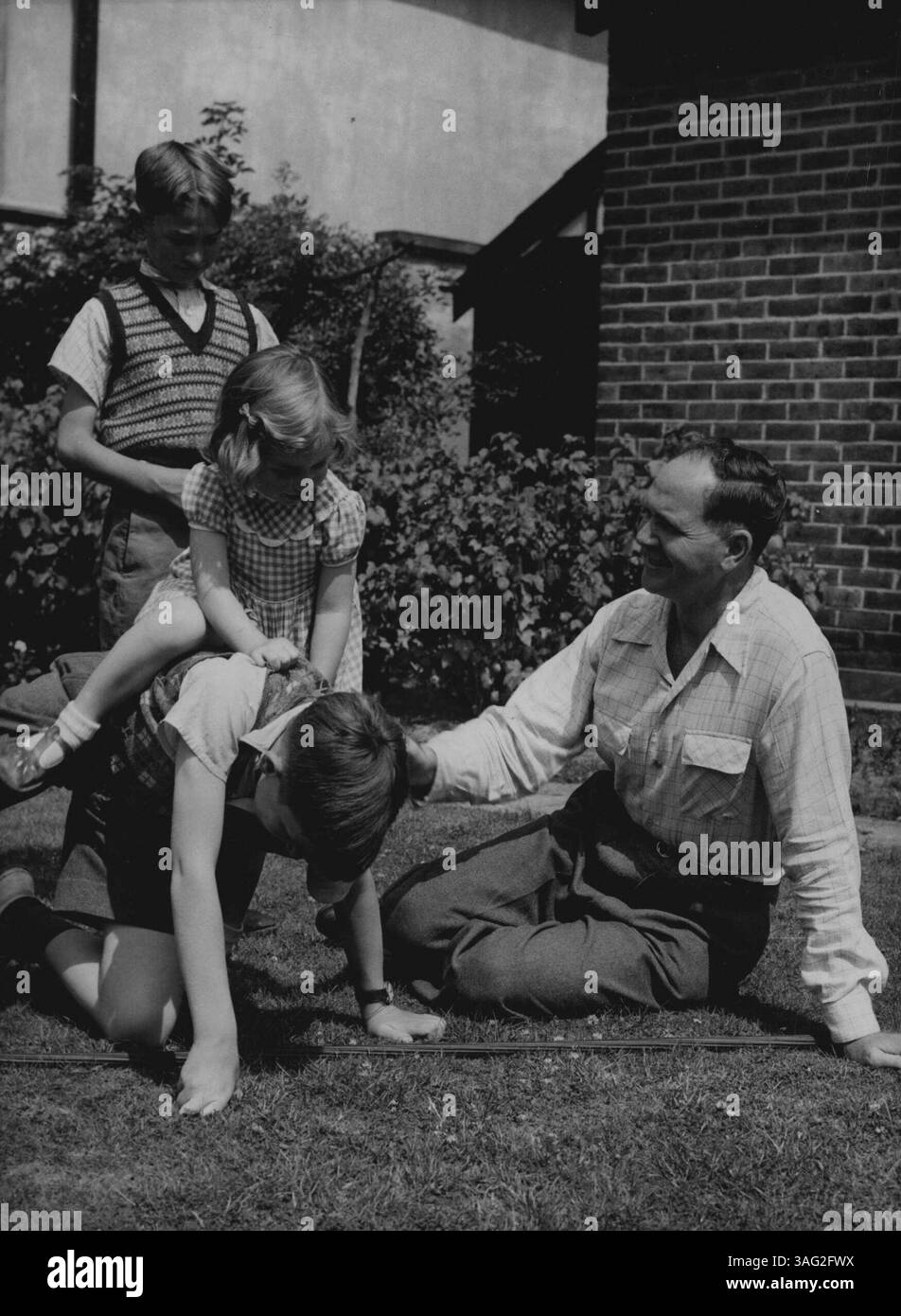 Le docteur Eric H.S. Burshop, le scientifique arom âgé de 40 ans dont le passeport a été saisi par le ministère britannique des Affaires étrangères peu de temps avant son départ pour un voyage à Moscou, est photographié ici en jeu avec ses enfants i sur le terrain de sa maison à Surbiton, Surrey, aujourd'hui 22 juillet. Les enfants sont la 12e année, qui donne un tour à Annalist, 3 ans, surveillé par Ian, 0 ans, de la BCK. 01 juillet 1951 (photo par Associated Press) Banque D'Images