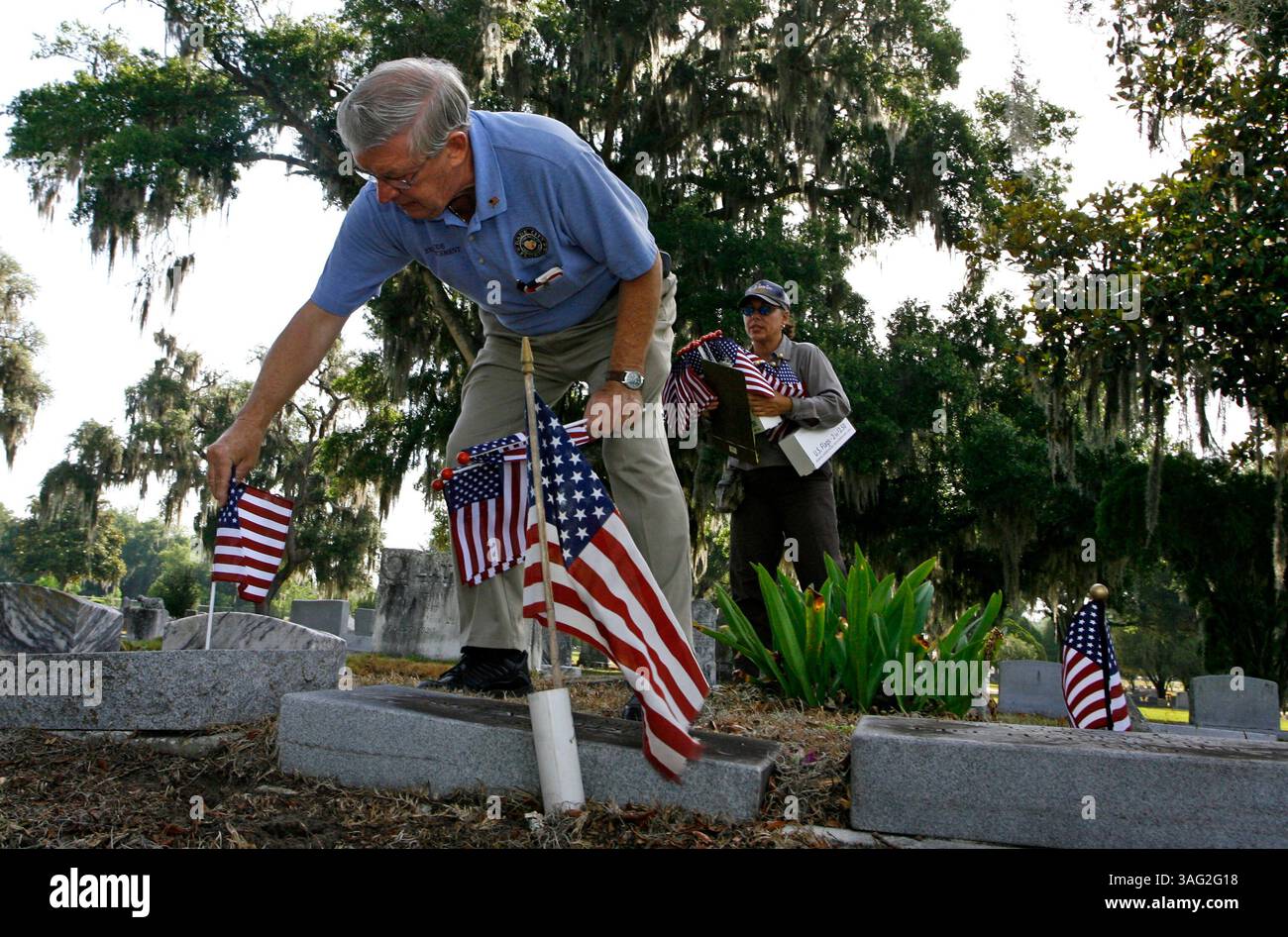 LÉGENDE : (Dade City 05/21/2008) Edward Gorecki (cq) un résident de Dade City et un agent d'application de la loi à temps partiel et vétéran de la Force aérienne place un drapeau sur la tombe d'un vétéran au cimetière de Dade City tandis que la gardienne du cimetière Mariarose Kussler se tient derrière lui avec une presse-papiers des tombes des vétérans et un bras plein de drapeaux américains. .. (Crédit image : St Petersburg Times/ZUMAPRESS.com) Banque D'Images