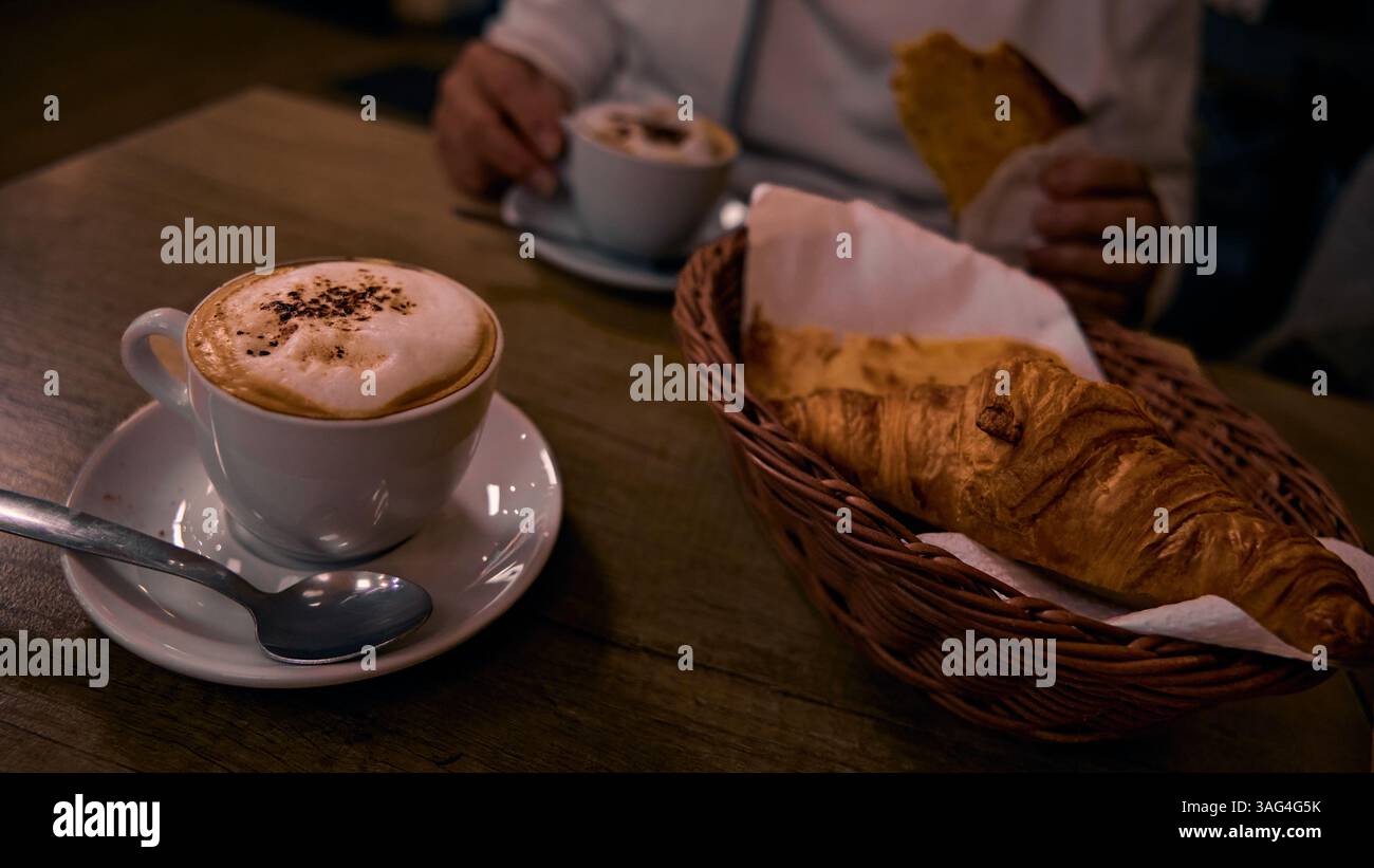 Tasse de cappuccino et croissant sur une table en bois. Banque D'Images