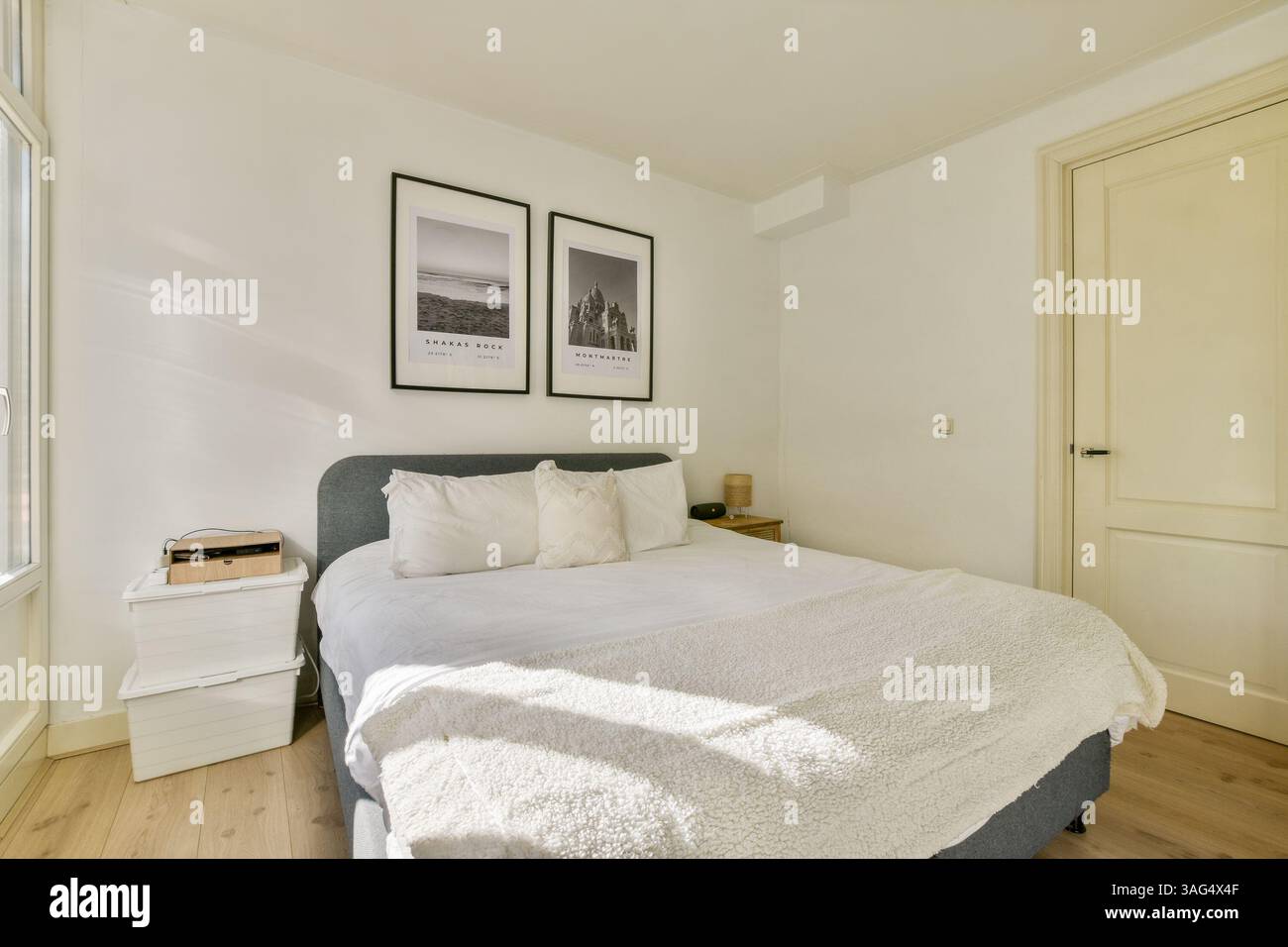 Cette chambre moderne et élégante dispose d'un lit orné de draps doux, de gravures d'art encadrées sur le mur et d'une ambiance chaleureuse créée par la lumière naturelle. Banque D'Images