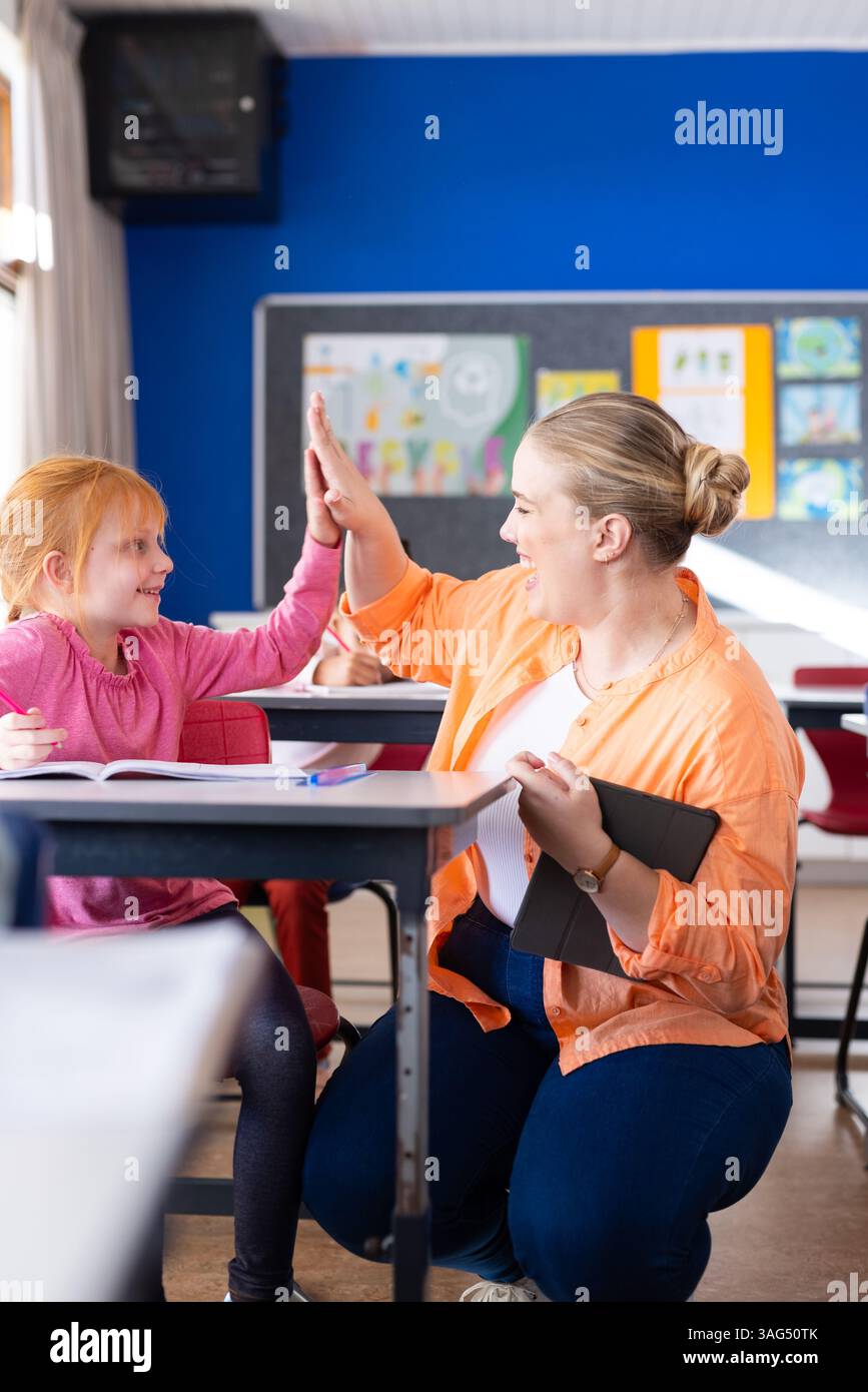 À l'école, enseignante fille de haut-cinq tout en tenant tablette dans la classe Banque D'Images