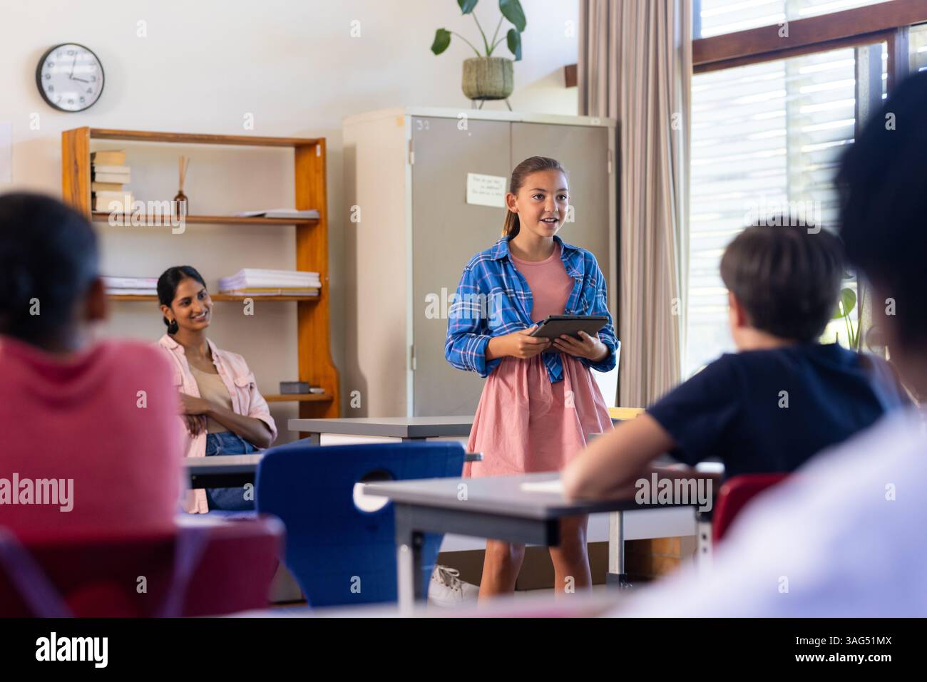 À l'école, fille présentant avec tablette en classe, s'engageant avec les élèves Banque D'Images