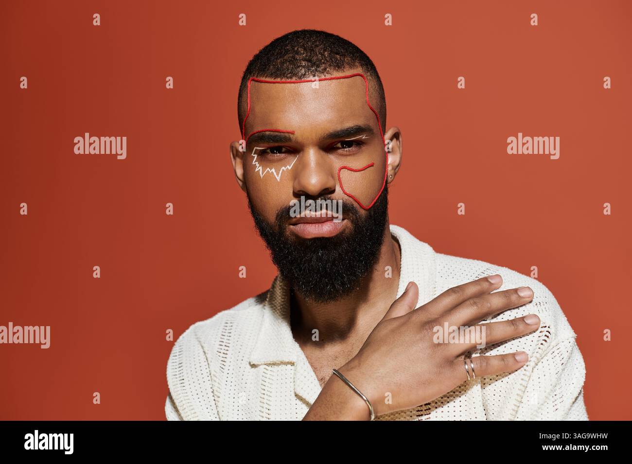 Jeune homme met en valeur son sens de la mode avec des arts du visage audacieux et une pose détendue contre des couleurs vives. Banque D'Images