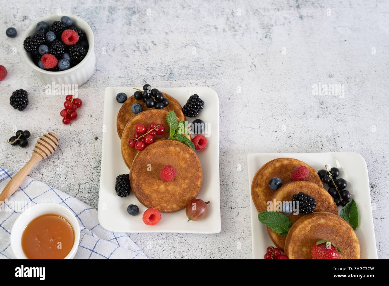 Crêpes brun doré avec des fruits frais élégamment disposées sur un plat blanc carré sur un plateau de table gris Banque D'Images Crêpes brun doré avec des fruits frais élégamment disposées sur un plat blanc carré sur un plateau de table gris Banque D'Images