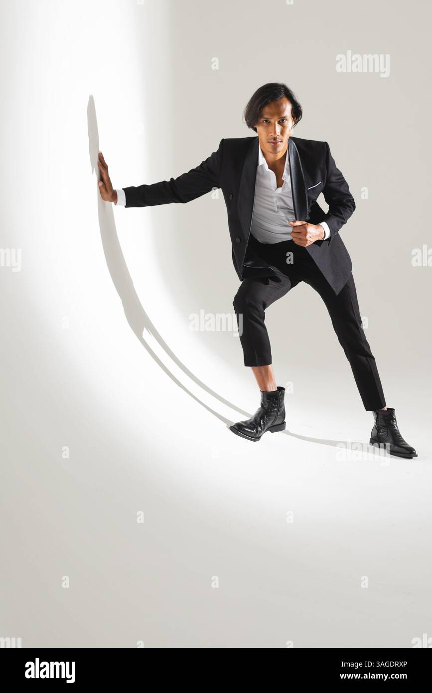 Homme confiant en costume élégant posant dynamiquement dans un studio moderne. Affaires, professionnel, mode, élégance, confiance, entreprise Banque D'Images