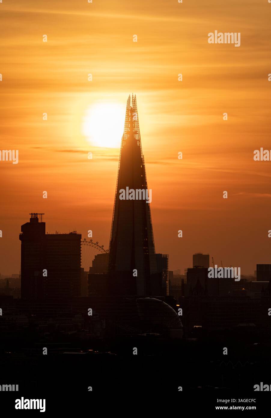 Le gratte-ciel Shard se dessinait contre un coucher de soleil orange vif à Londres, au Royaume-Uni, avec le coucher du soleil derrière le bâtiment et le London Eye Banque D'Images