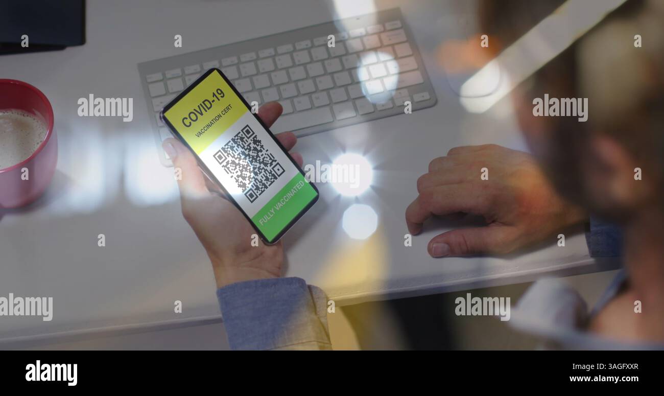 Image d'un homme tenant un smartphone avec un passeport de vaccination covid 19 sur des lumières floues Banque D'Images