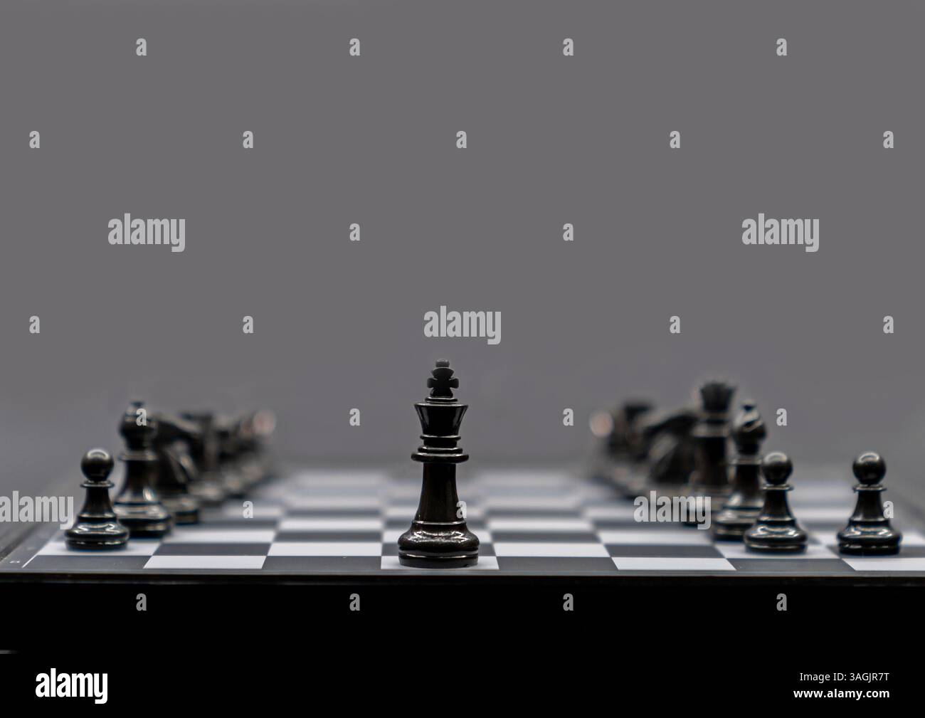 Concept de leadership, roi noir des échecs, se démarquant de la foule de noir sur fond sombre. Banque D'Images