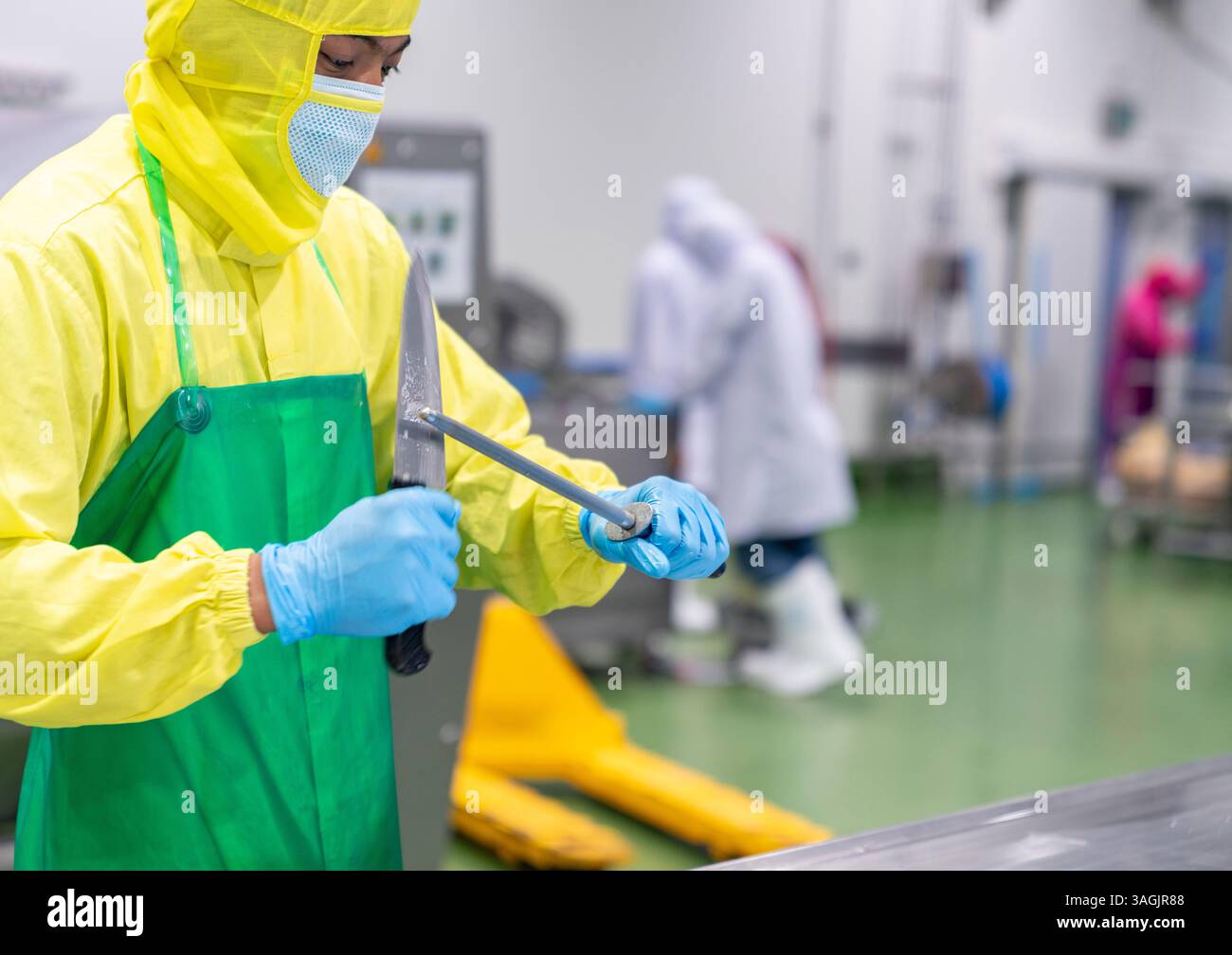 Ouvrier remplissant un couteau avec une râpe dans la chaîne de production. Banque D'Images