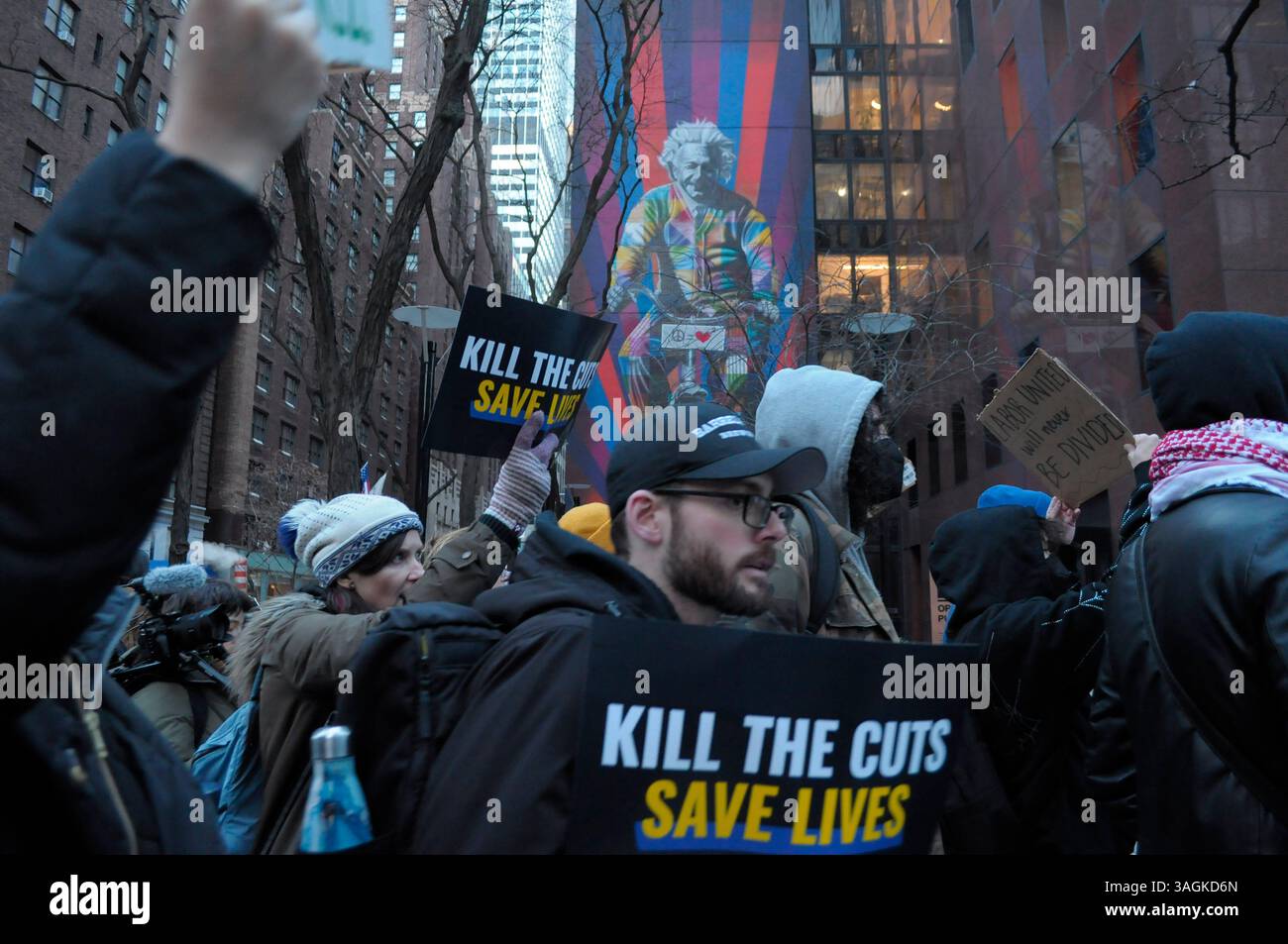 Les manifestants défilent en tenant des pancartes devant une murale d'Albert Einstein. Des manifestants à Manhattan ont protesté contre l’administration Trump pour avoir coupé les fonds destinés aux soins médicaux et à la recherche. Les manifestants ont également critiqué Elon Musk, le chef du département de l'efficacité du gouvernement, DOGE, pour avoir licencié des employés fédéraux et coupé les services fédéraux. Selon les manifestants, les coupes fédérales dans les fonds qui vont aux Instituts nationaux de la santé nuisent à la recherche médicale sur des maladies comme le cancer, la maladie d'Alzheimer et le diabète. Les manifestants ont également déclaré que les coupes budgétaires nuiraient à l'éducation des étudiants universitaires Banque D'Images