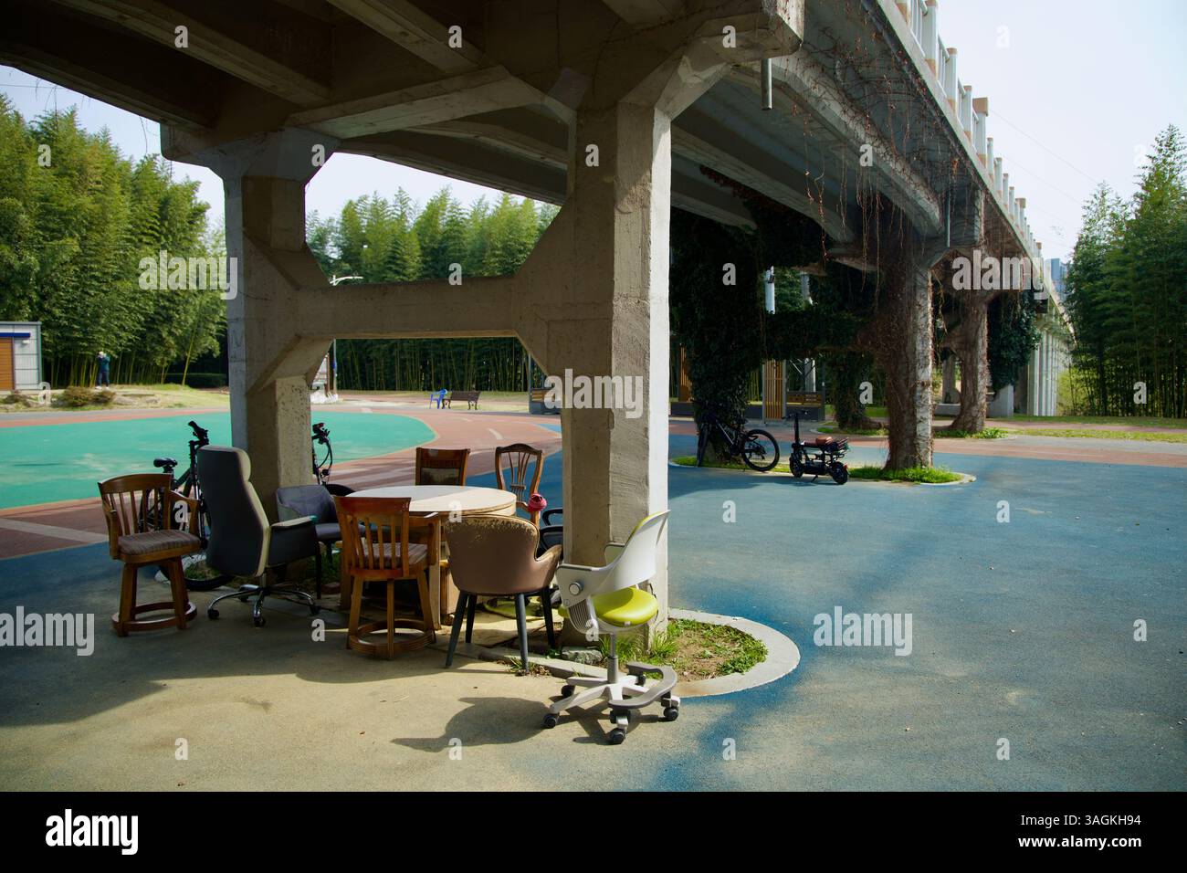 Ulsan City, Corée du Sud - 31 mars 2025 : un patchwork de chaises désassorties et une table circulaire crée une zone commune sous le pont près du Ta Banque D'Images