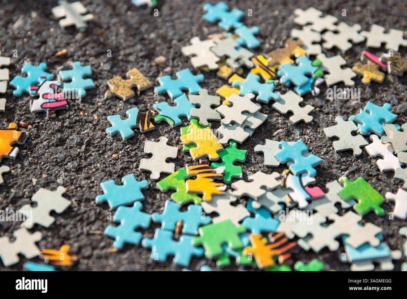 Une image de fond de pile de pièces de puzzle multicolores mélangées dispersées sur le pavé d'asphalte gris sur la rue. Concept chaotique désordonné. Cl Banque D'Images