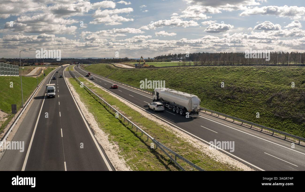Vue surélevée d'une autoroute à plusieurs voies mettant en vedette des véhicules en mouvement, bordée de barrières acoustiques, représentant des infrastructures, des réseaux routiers Banque D'Images