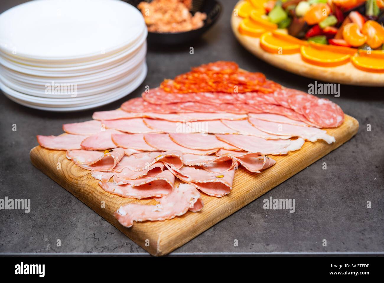 Planche en bois avec un assortiment de viandes séchées en tranches, y compris le salami, le jambon et la mortadelle, idéale pour les hors-d'œuvre ou les buffets. Banque D'Images