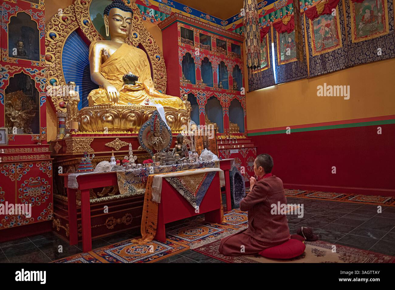 Une religieuse non identifiable médite par une belle statue du Bouddha Meitreya une représentation du futur Bouddha. Dans un temple du comté de Dutchess, NY. Banque D'Images