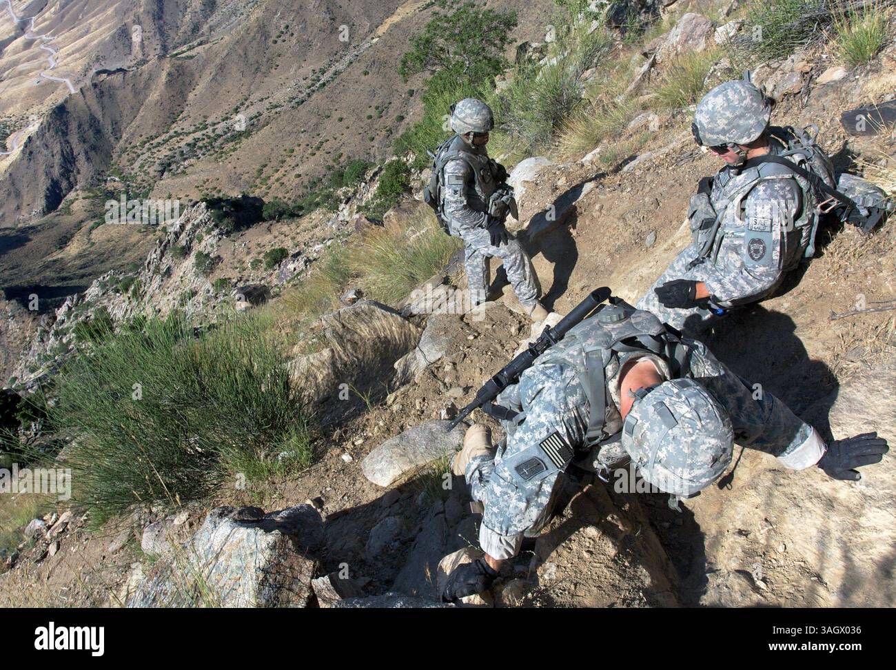 Juin 06, 2009 - Karagush, Nuristan, Afghanistan - les PO2 Chandler (en haut au centre) et PO2 Rodrigez (en haut à droite) s'arrêtent pour se reposer pendant que le SPC Segovia abaisse la tête pour se reposer lors d'une randonnée depuis la seule route de la région (vue dans le coin supérieur gauche) pour atteindre le poste d'observation Loyalty, contrôlé par l'Armée nationale afghane et l'Armée américaine. De nombreux avant-postes militaires ne sont accessibles qu'à pied ou en hélicoptère en raison du manque de routes. Les soldats sont souvent obligés de traverser des terrains difficiles et dangereux pour visiter des villages reculés rarement vus par les forces de sécurité. L'absence d'un tel se Banque D'Images