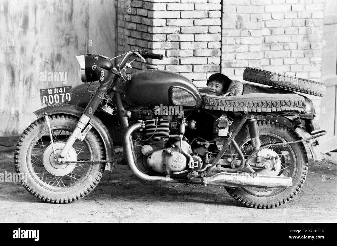 Mar 15, 1996 - Hezhou, province du Gansu, Chine - Le visage souriant d'un petit enfant qui regarde un 'Dong Hai', une marque chinoise de side-car de moto à Hezhou. (Crédit image : © Ruaridh Stewart/ZUMA Press) Banque D'Images
