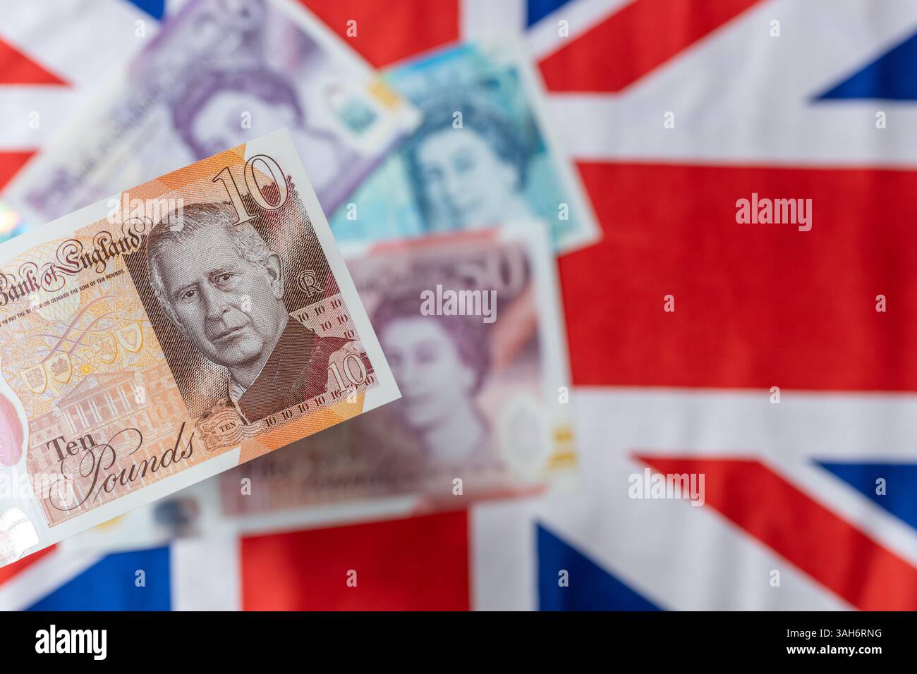 Nouvelle monnaie britannique avec le roi Charles III, émise pour la première fois en juin 2024 par la Banque d'Angleterre, Royaume-Uni. En arrière-plan, drapeau et billets plus anciens avec l'ima Banque D'Images