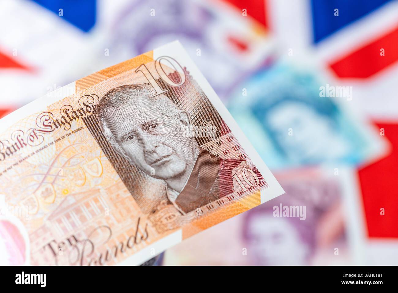 Nouvelle monnaie britannique avec le roi Charles III, émise pour la première fois en juin 2024 par la Banque d'Angleterre, Royaume-Uni. En arrière-plan, drapeau et billets plus anciens avec l'ima Banque D'Images