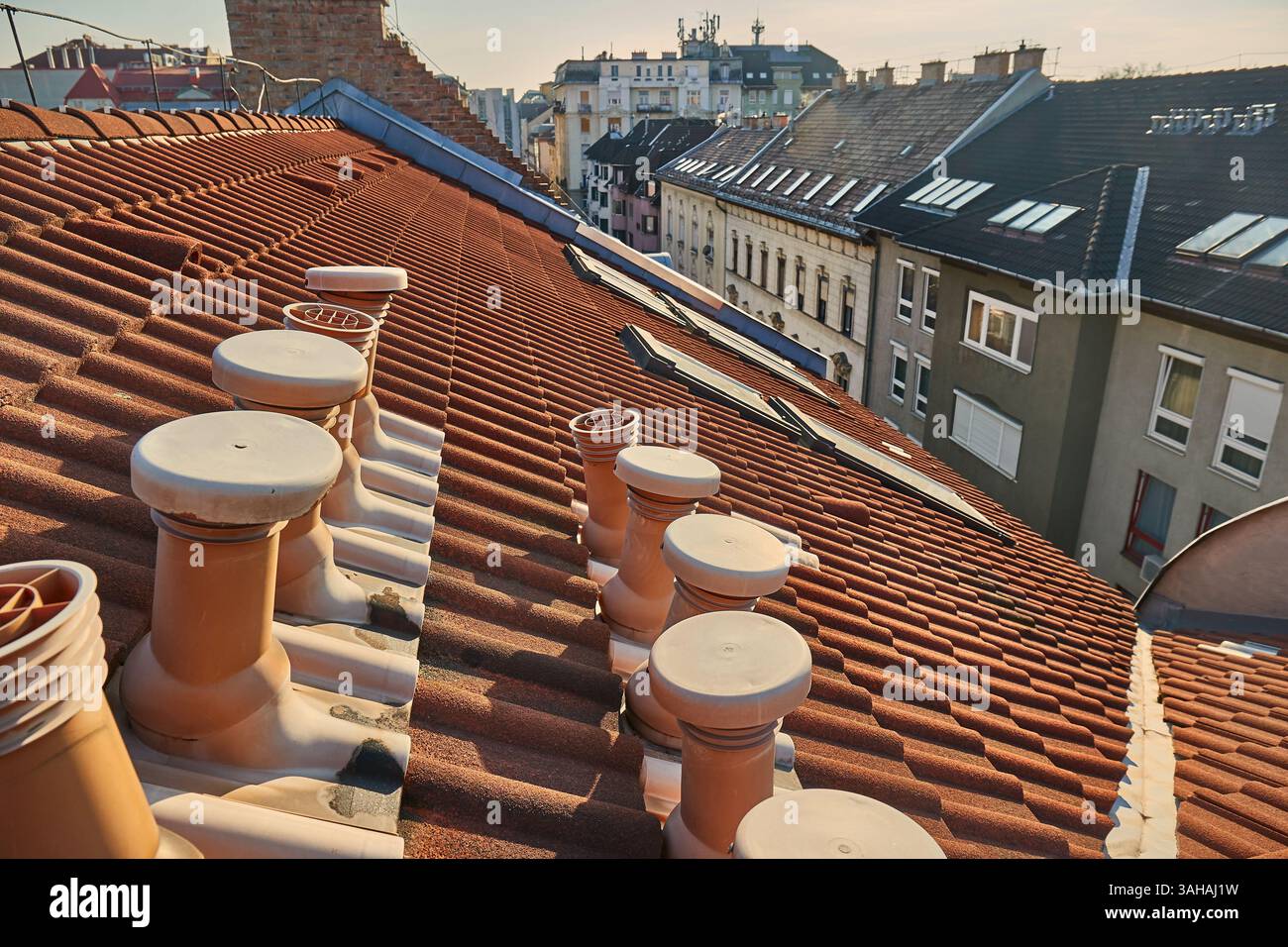 Toits carrelés de bâtiments urbains avec conduits d'aération Banque D'Images
