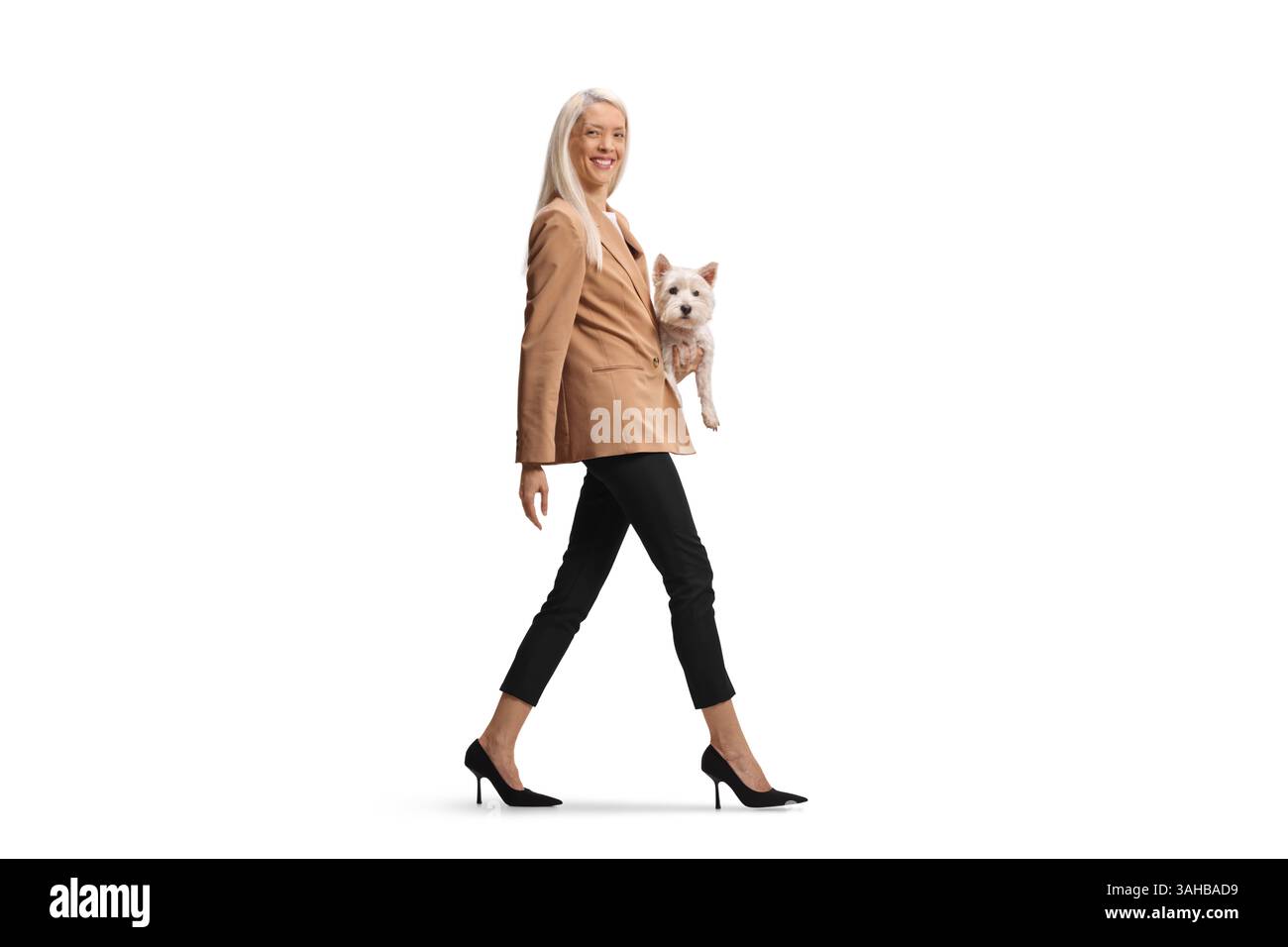 Femme heureuse portant un chien et marchant isolé sur fond blanc Banque D'Images