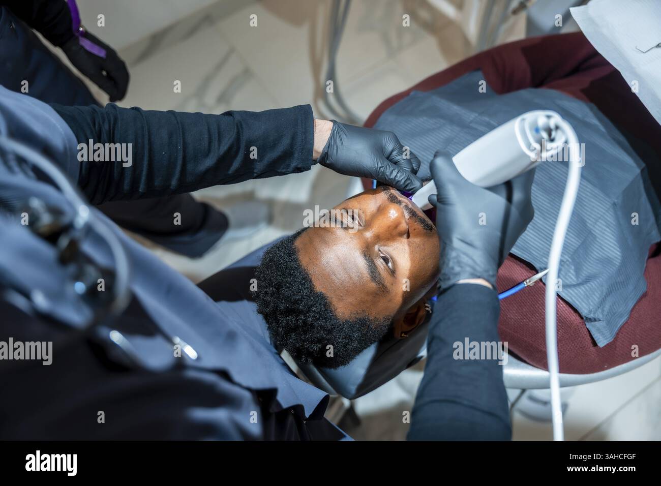 Dentiste utilise une lampe de blanchiment des dents professionnelle, améliorant le sourire d'un patient dans une clinique dentaire de pointe Banque D'Images