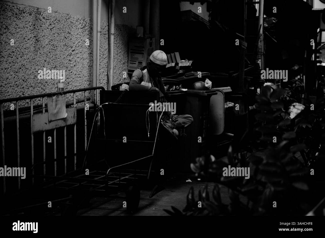 Un éboueur prend un moment de repos dans l'ombre d'une ruelle de Bangkok Banque D'Images