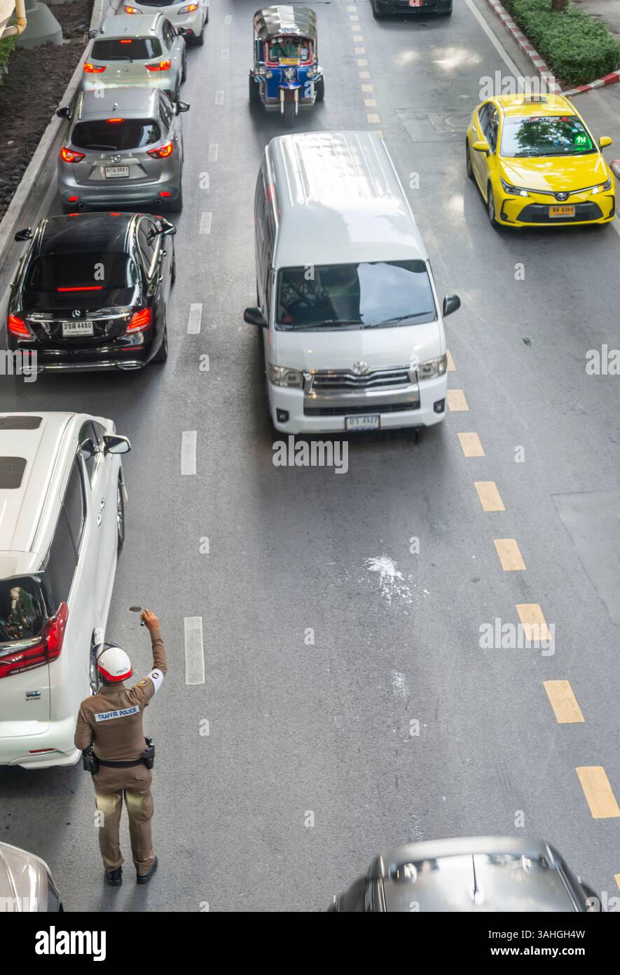 Thaïlande-03 juillet 2024 : le trafic routier conjesté se déplace lentement, comme un flic de la circulation tente de contrôler le flux des véhicules. Banque D'Images
