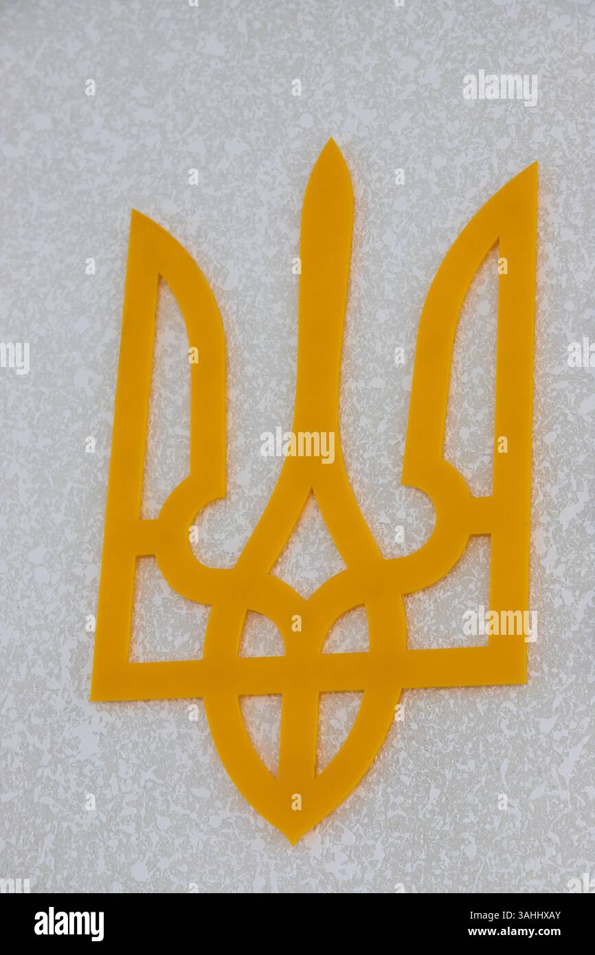 Le symbole de trident jaune vif orne une surface texturée de couleur claire, signifiant l'identité nationale ukrainienne et la fierté culturelle. Cet emblème est un bal Banque D'Images