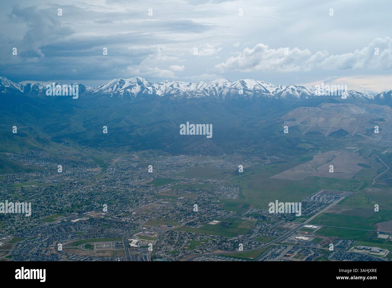 Vue aérienne d'un paysage urbain tentaculaire avec des montagnes enneigées sous un ciel nuageux. Oregon, États-Unis Banque D'Images