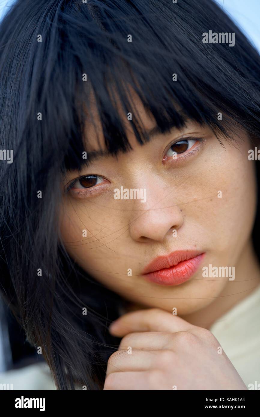 Gros plan d'une femme avec de longs cheveux noirs et du rouge à lèvres rouge vif regardant intentionnellement. Brandebourg, Allemagne Banque D'Images