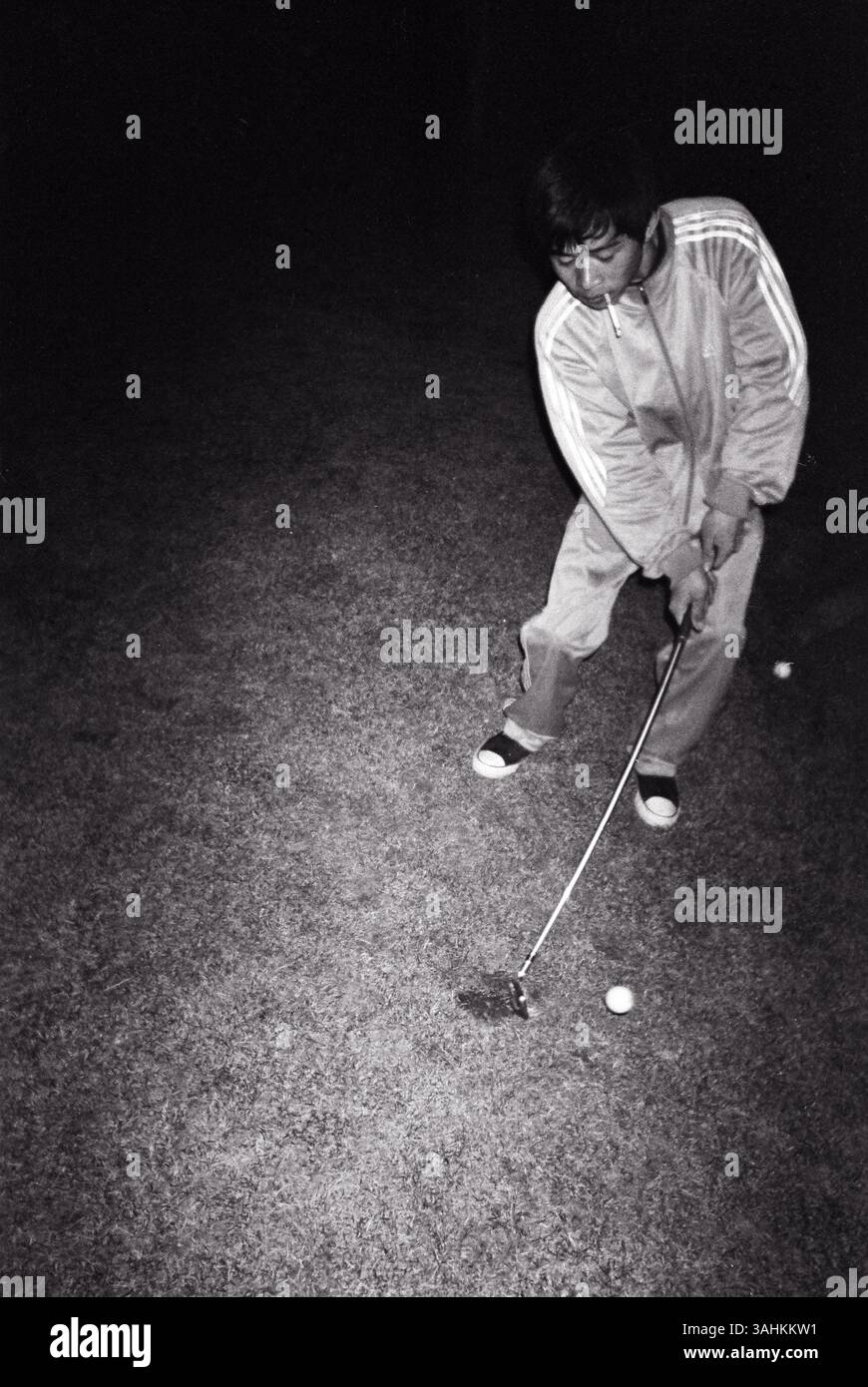 A Golf Caddy’s Midnight Lesson on the Green – Un débutant de la classe ouvrière pratiquant secrètement au cœur d’un sport exclusif, Pékin, Chine, 2013. Banque D'Images