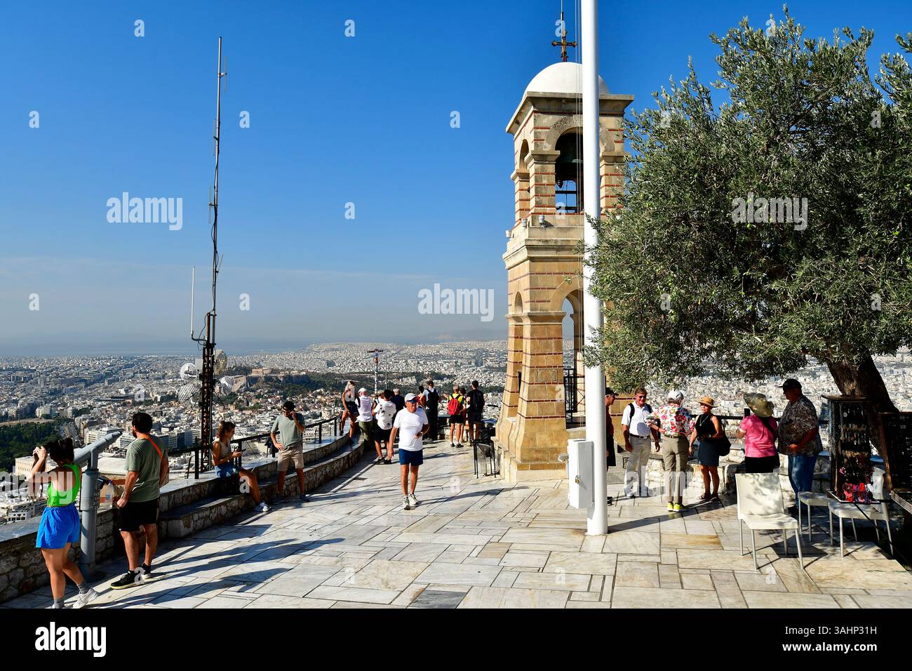 Athènes, Grèce - 23 septembre 2024 : touristes non identifiés et clocher sur la terrasse d'observation de la colline Lycabette avec panorama sur la mer de ​​house Banque D'Images