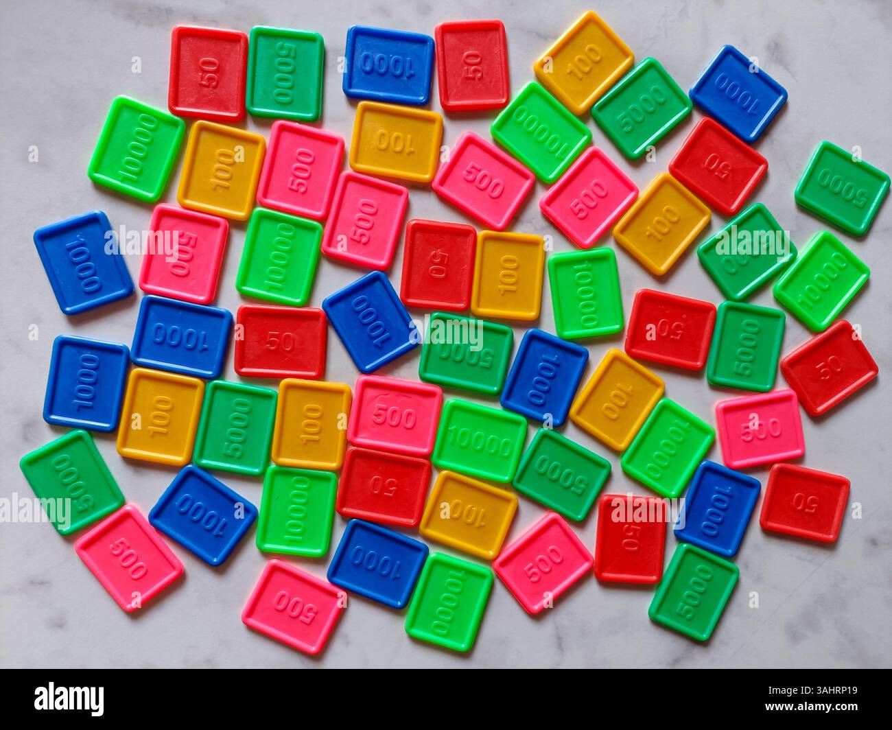 jeton de style casino en plastique coloré ou jetons d'argent de jeu. Les jetons viennent dans des couleurs primaires vives avec un numéro écrit dessus sur un fond de marbre Banque D'Images