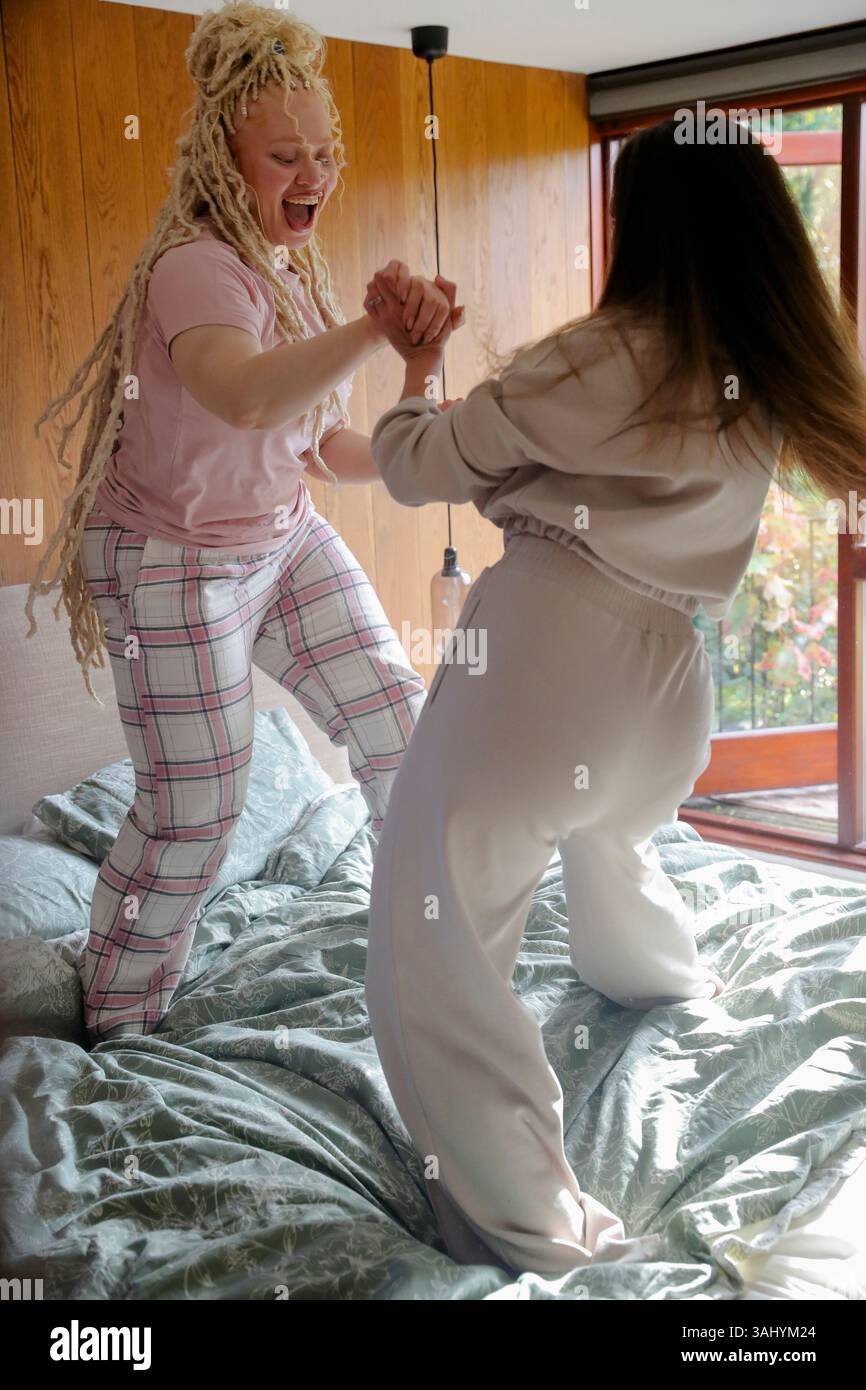 Amis souriants dansant sur le lit Banque D'Images