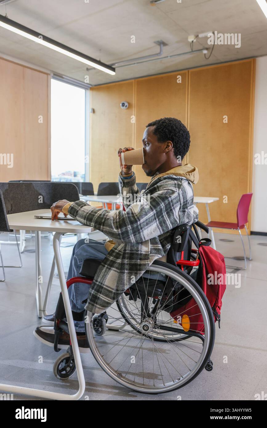 Homme en fauteuil roulant au bureau dans le bureau Banque D'Images