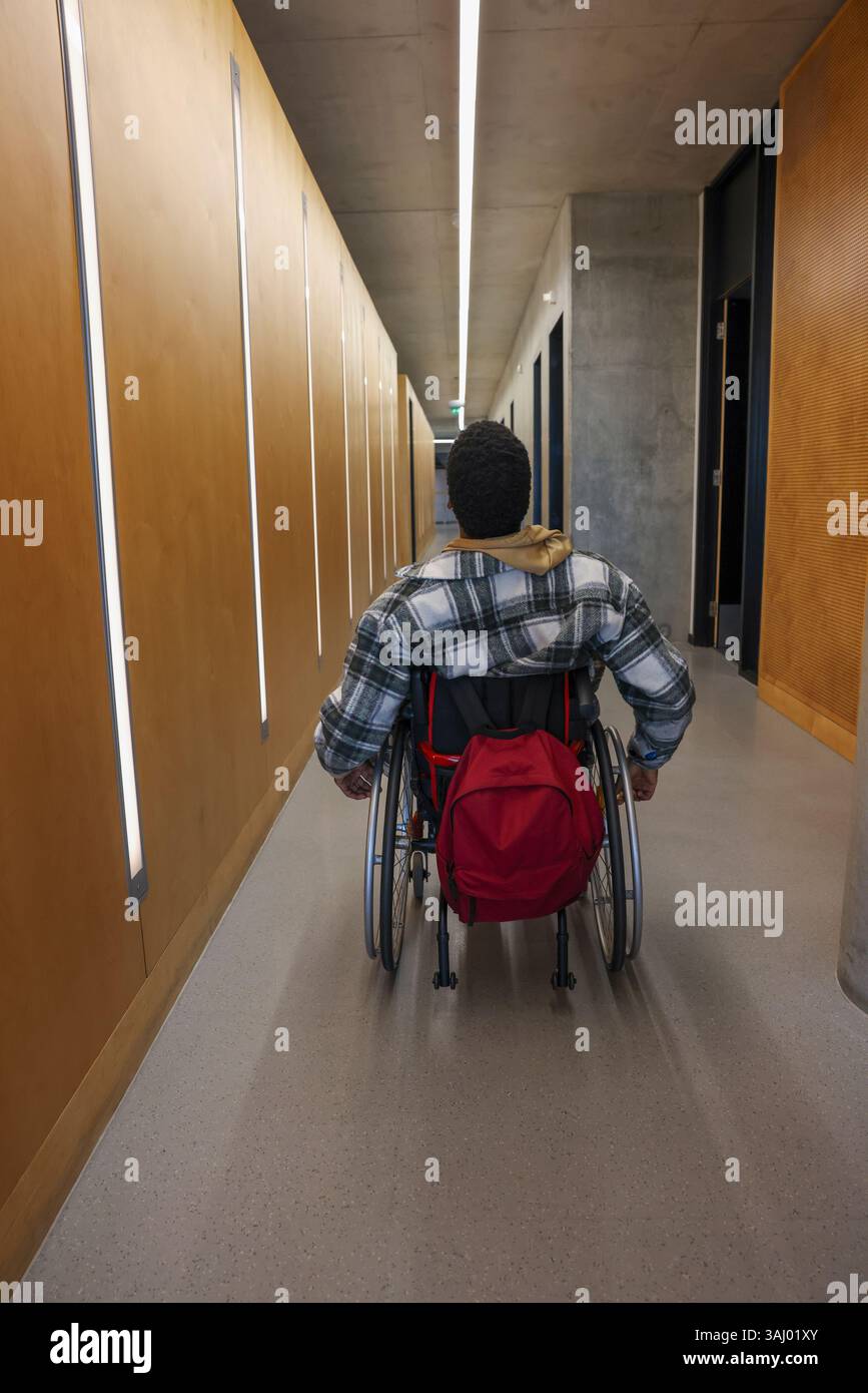 Homme en fauteuil roulant dans le couloir du bureau Banque D'Images