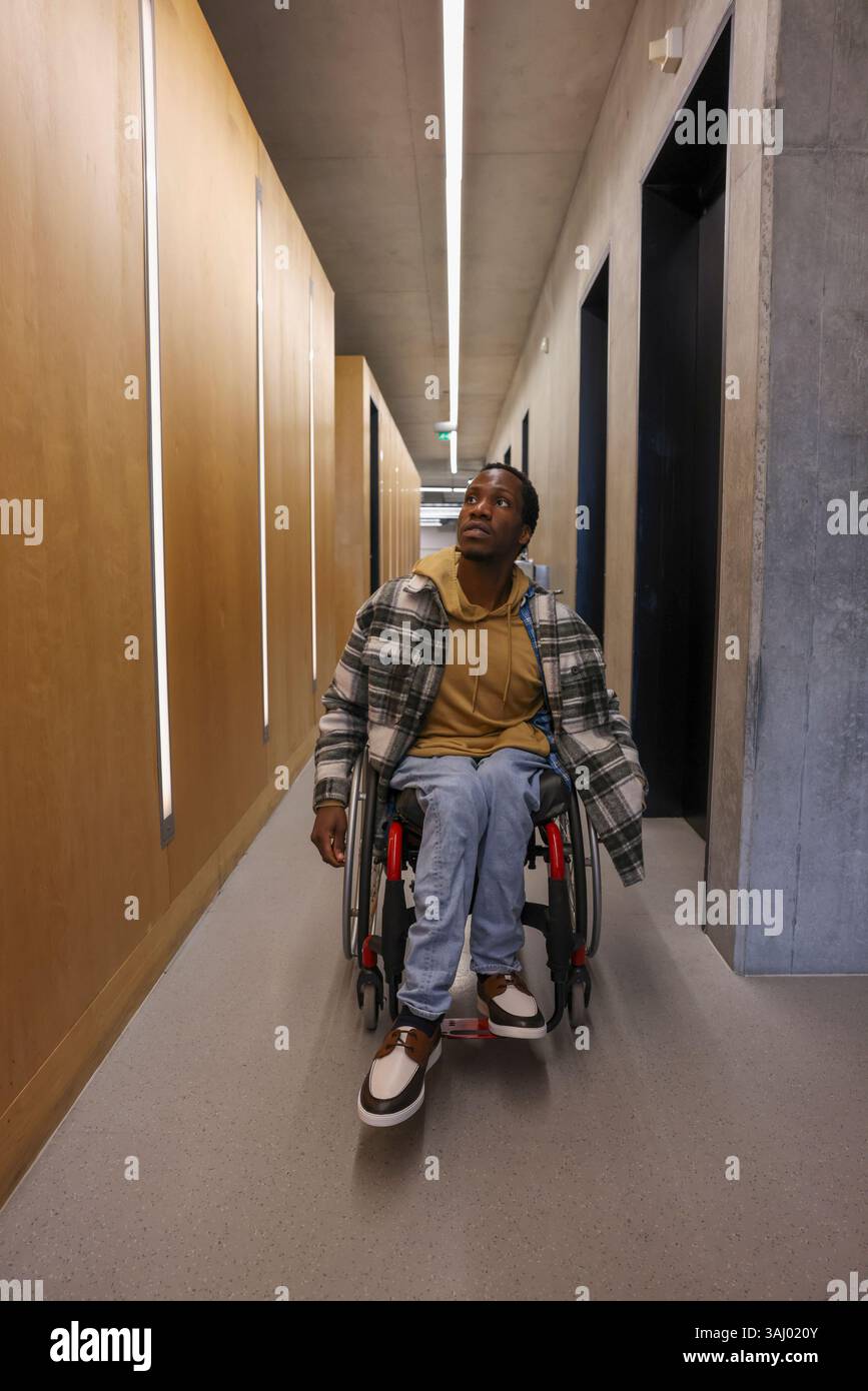 Homme en fauteuil roulant dans le couloir du bureau Banque D'Images