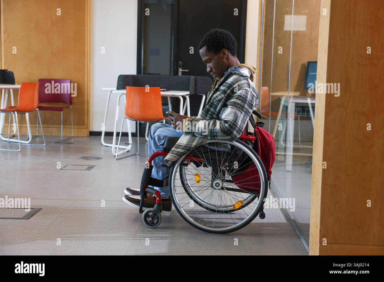 Homme en fauteuil roulant regardant le téléphone intelligent dans le bureau Banque D'Images