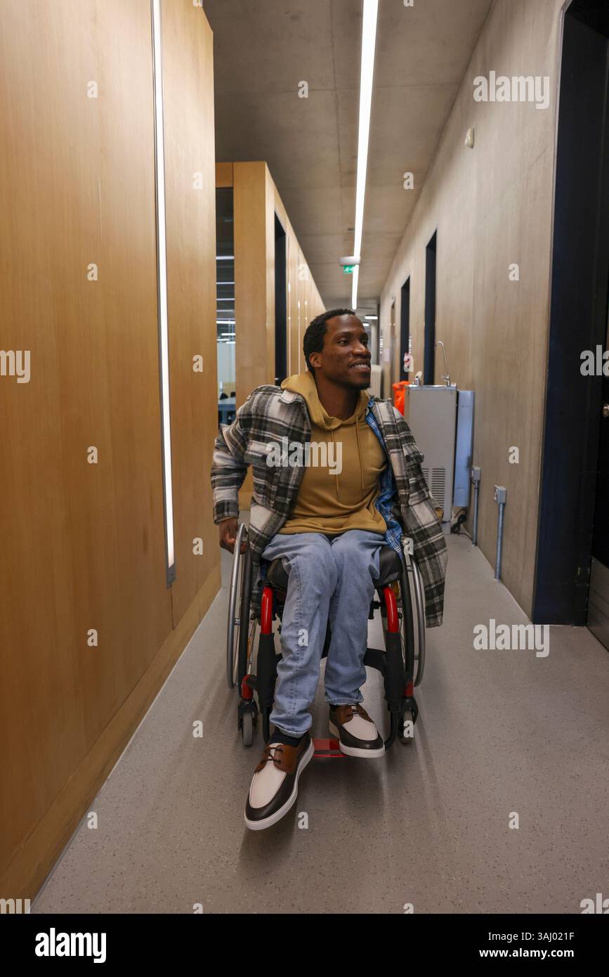 Homme en fauteuil roulant dans le couloir du bureau Banque D'Images