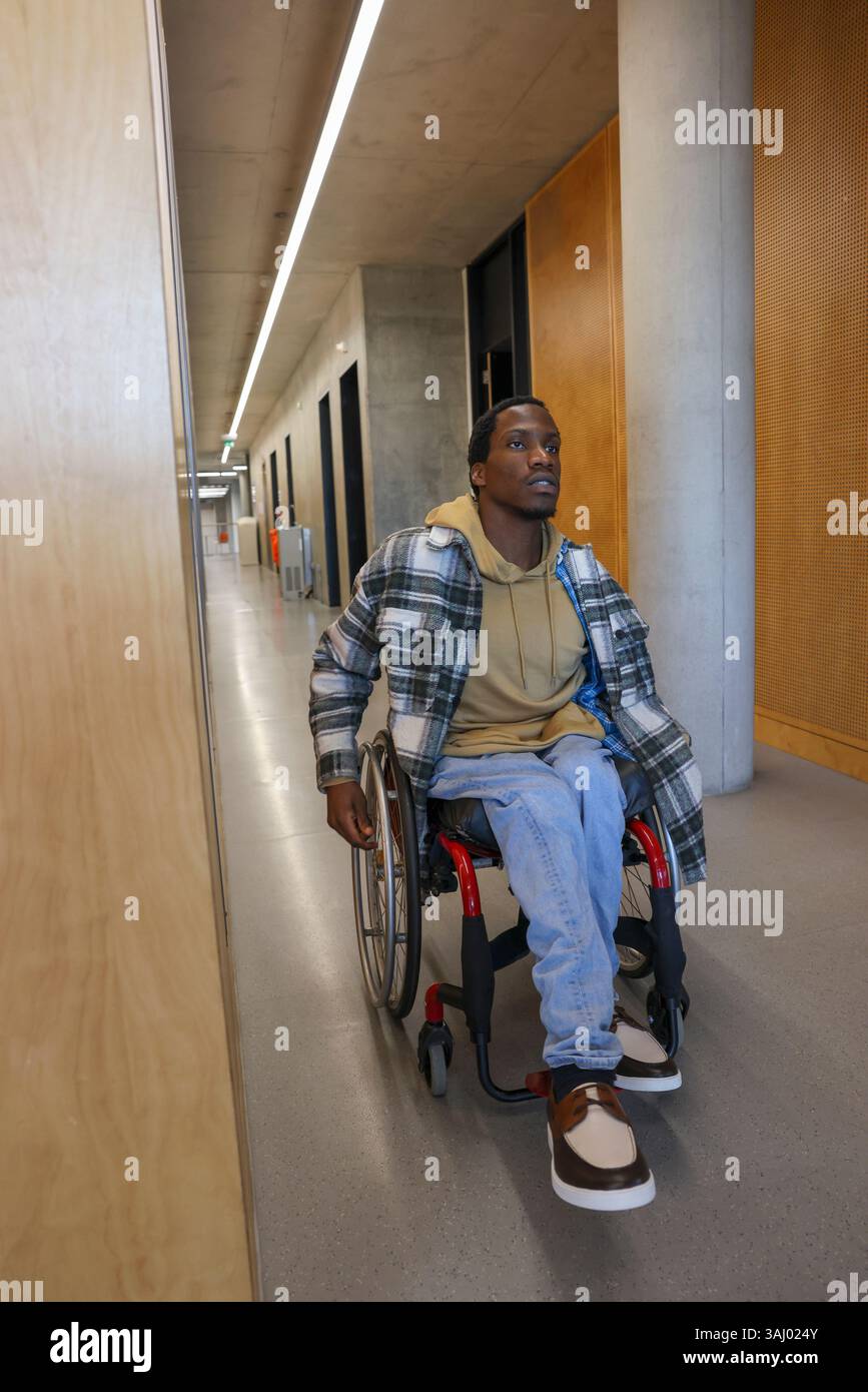 Homme en fauteuil roulant dans le couloir du bureau Banque D'Images
