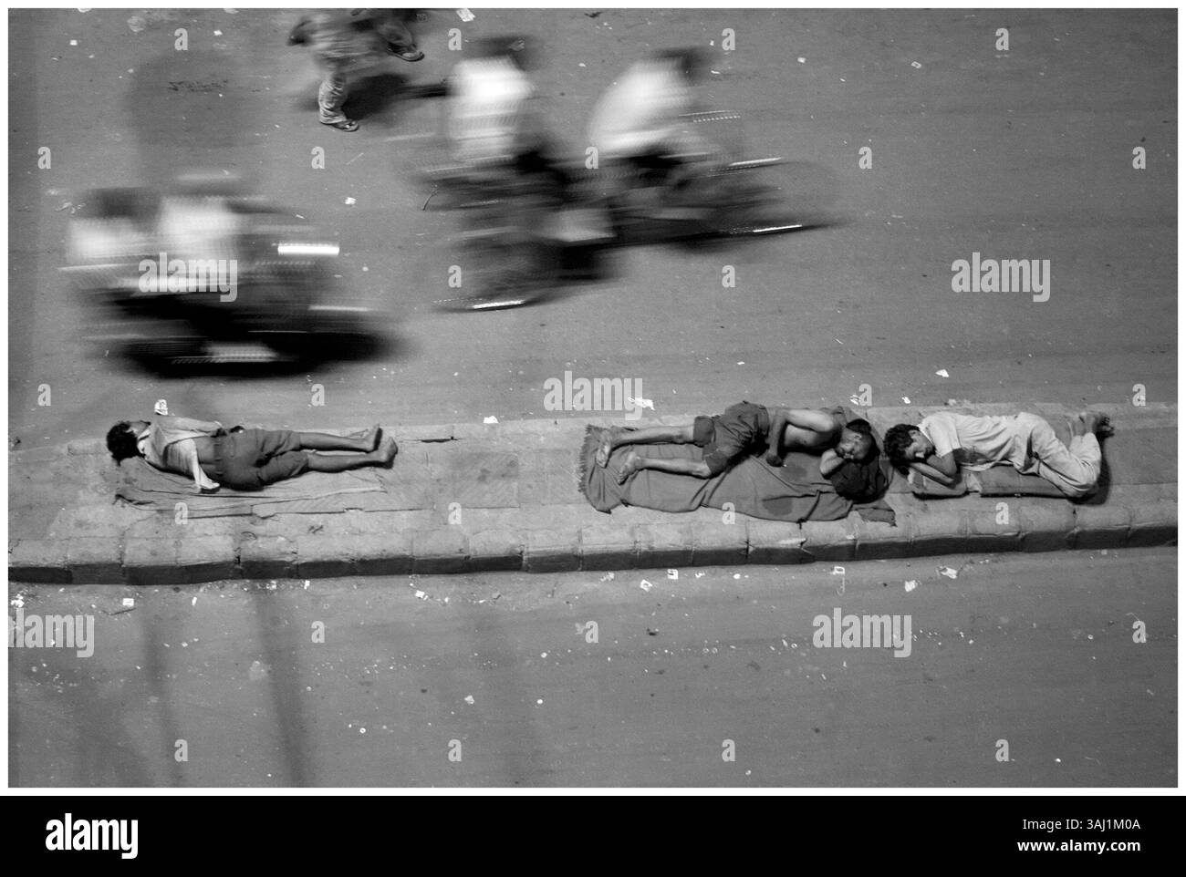 Juin 2, 2009 - Delhi, Inde - travailleurs migrants dormant sur une cloison routière. La construction est le plus grand secteur en Inde après l'agriculture. La plupart des emplois dans la construction proviennent de travailleurs migrants. Les heures de travail sont du lever au coucher du soleil. La journée de travail des femmes s'étend souvent de 14 à 16 heures, combinant travail domestique et travail sur le site. Là, ils sont payés 100 à 150 roupies par jour tandis que les hommes sont payés 200 à 250 roupies. Les maçons gagnent jusqu'à 300 à 350 roupies par jour. Le lieu de travail est dangereux. Les travailleurs n'ont pas de sécurité sociale, pas d'indemnisation pour les blessures, pas d'accès à l'eau potable et n Banque D'Images