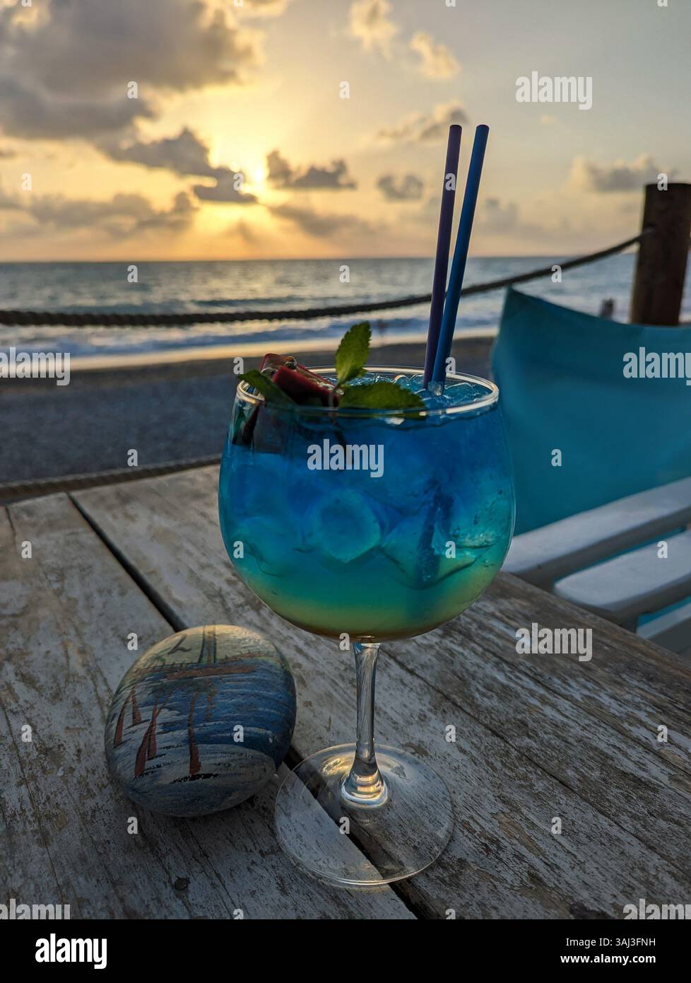 Cocktail bleu au Sea You Beach Bar, Kissonerga, Chypre, apprécié lors d'un coucher de soleil doré au bord de la mer. - Image de stock capturée avec un smartphone