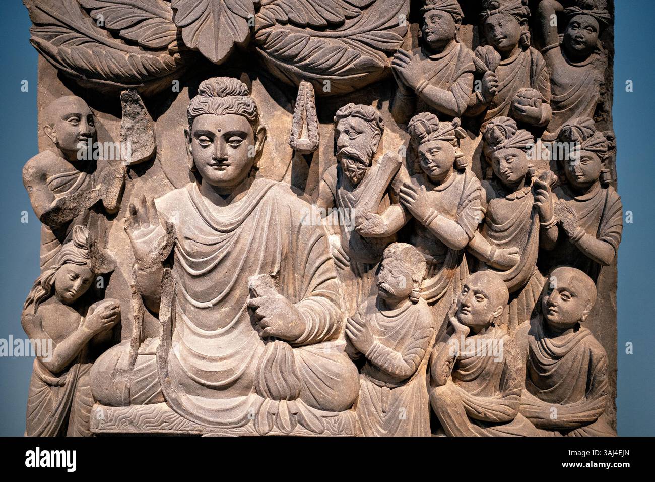 WASHINGTON DC — Un panneau en relief de schiste de l'ancien Gandhara (Pakistan/Afghanistan moderne) représentant le Bouddha livrant son premier sermon, exposé au Smithsonian National Museum of Asian Art. Créé sous la dynastie Kushan (fin du IIe siècle - début du IIIe siècle de notre ère), ce panneau faisait partie d'un ensemble de quatre scènes ornant un stupa bouddhiste. La sculpture montre le Bouddha avec sa main levée dans un geste de réconfort, entouré de disciples attentifs qui se distinguent par leur apparence - des disciples laïcs portant des bijoux et des moines à tête rasée sans ornements. Banque D'Images