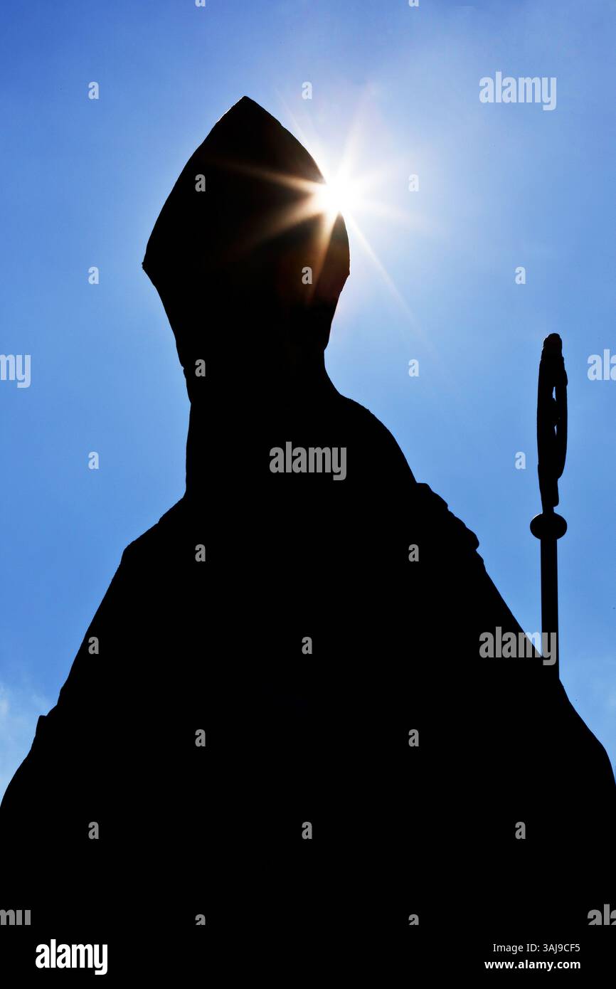 Évêque catholique anonyme avec mitre et crozier comme une silhouette contre la lumière, photo symbolique Banque D'Images
