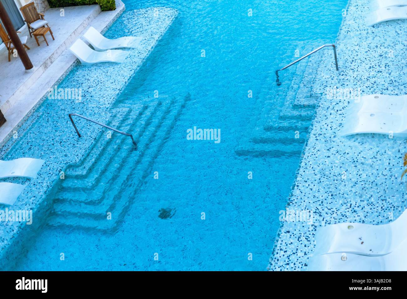 Les nageurs profitent d'une expérience rafraîchissante dans les eaux turquoises invitantes d'une piscine immaculée, tandis que les marches mènent à la surface chatoyante sous le Banque D'Images