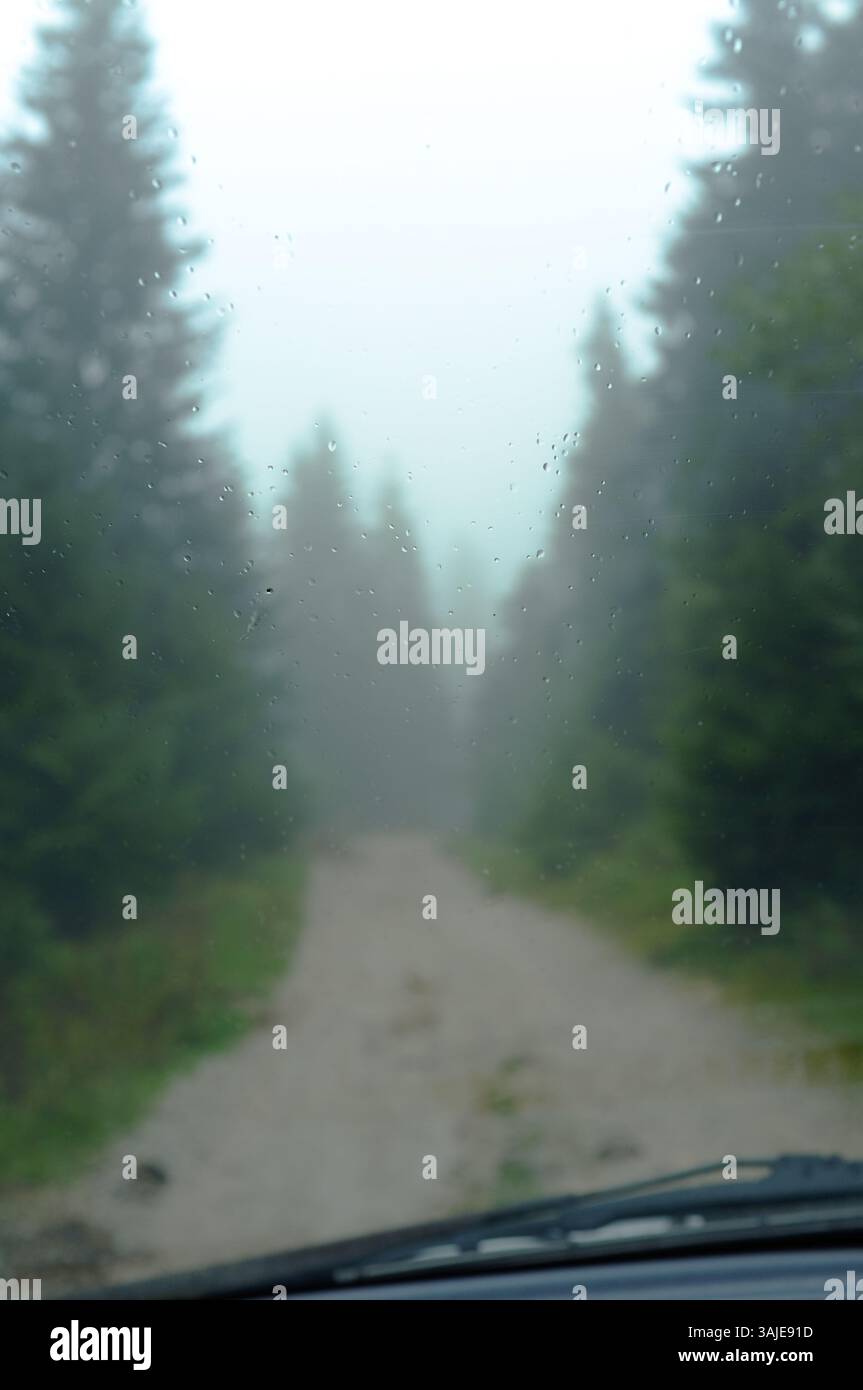 Gouttes de pluie sur le pare-brise d'une voiture, dans le fond flou une forêt d'automne sur une route de campagne à Ravna Romanija, Bosnie-Herzégovine Banque D'Images
